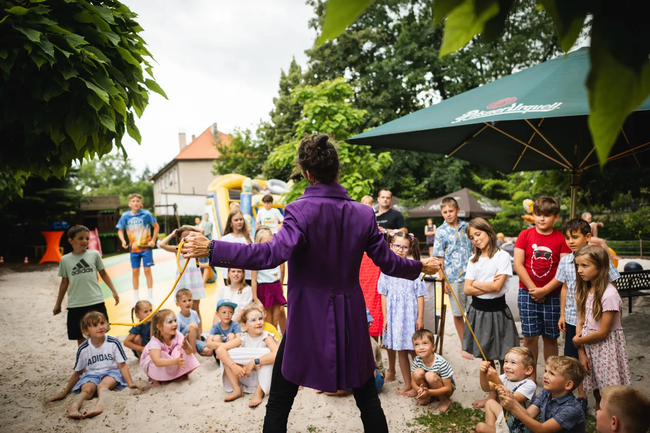 kouzelník zapojuje děti do vystoupení během akce po vysvědčení